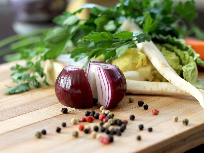 A cinematic aerial shot of fresh organic vegetables, mushrooms, and herbs scattered on a rustic wooden table with soft side lighting, no woman